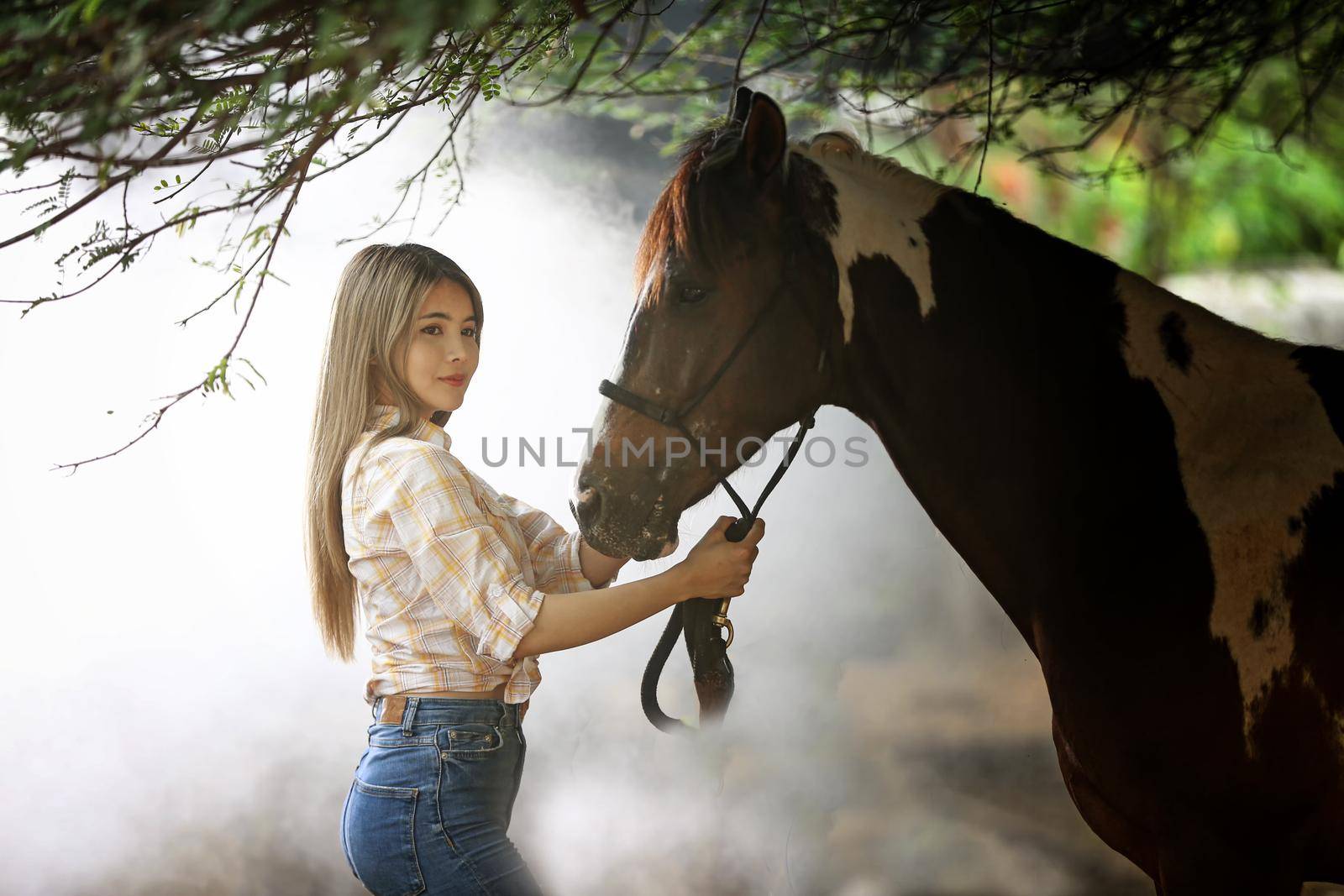 A woman in a cowgirl style sits in a horse ranch with a western farm environment.