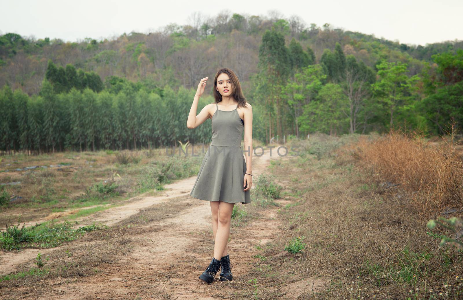 A beautiful woman with long hair in a dress sitting on a meadow and flowers in the evening light.