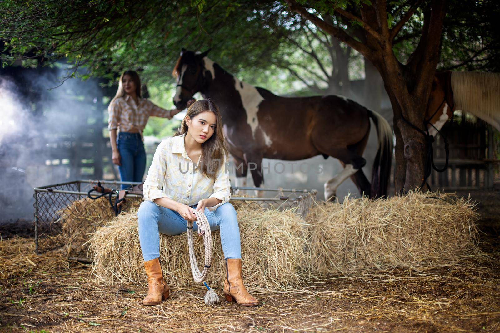 A woman in a cowgirl style sits in a horse ranch with a western farm environment. by chuanchai