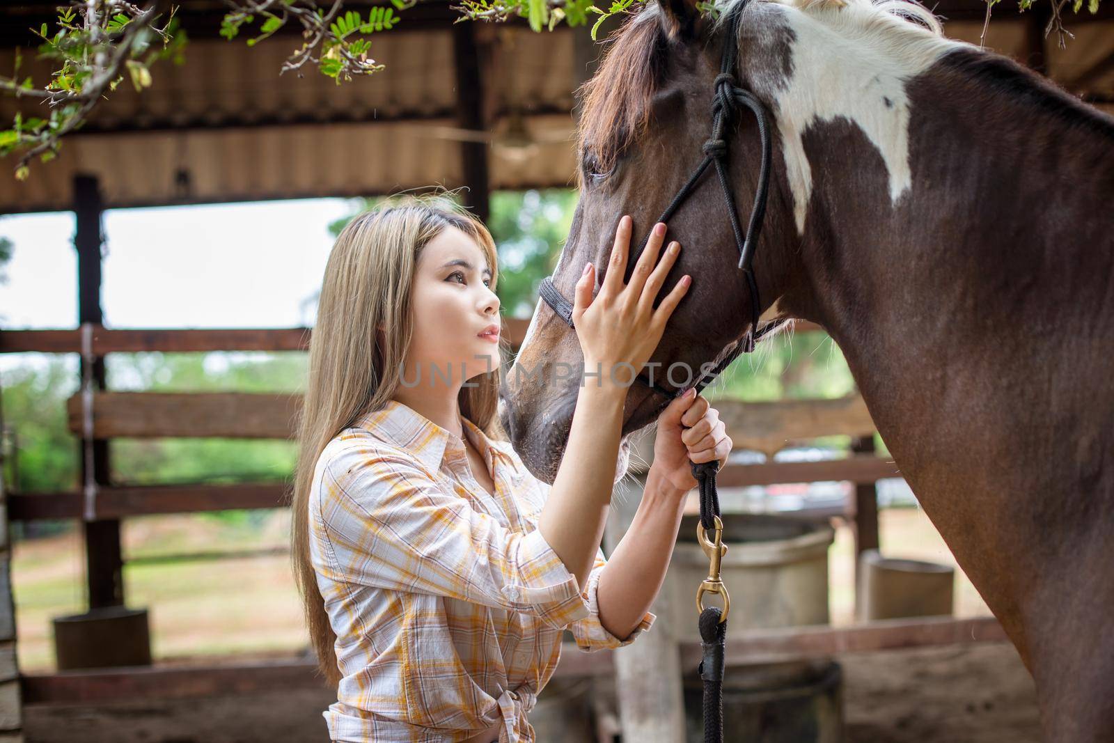 A woman in a cowgirl style sits in a horse ranch with a western farm environment.