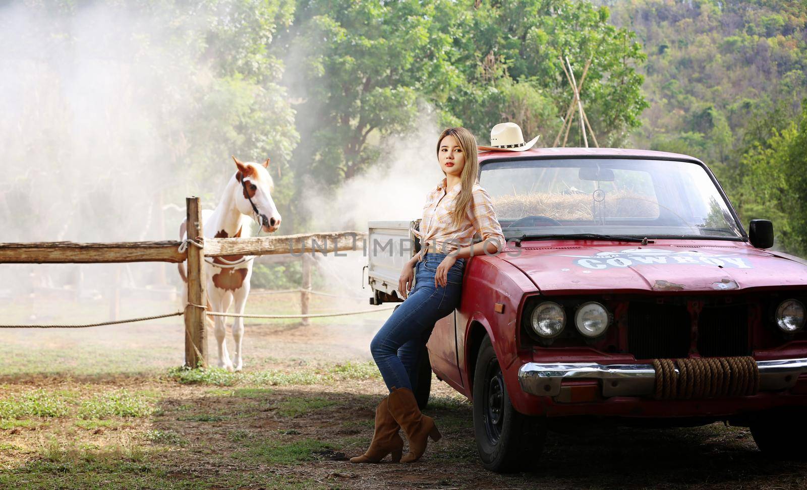 A woman in a cowgirl style sits in a horse ranch with a western farm environment.