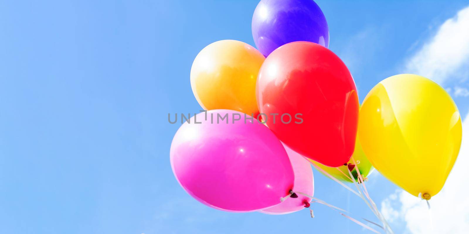 Outdoors party decoration concept - mix of colorful balloons on a blue sky background with copy space.