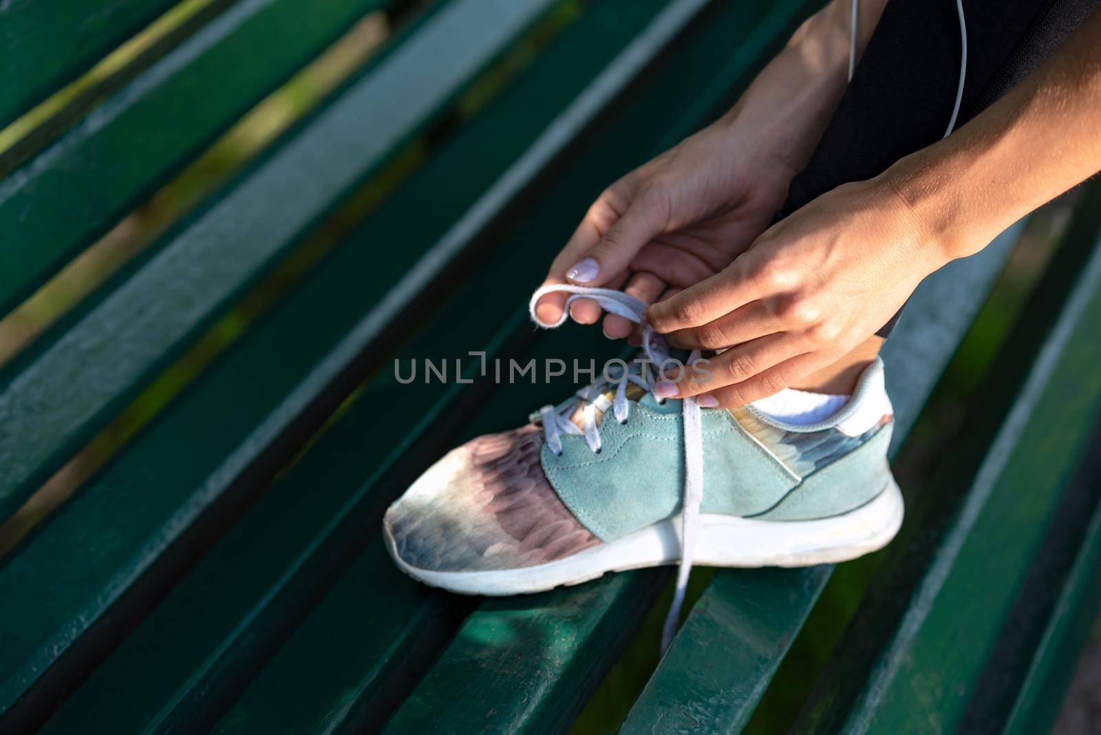 Runner woman tying shoelaces on bench during workout in the park.