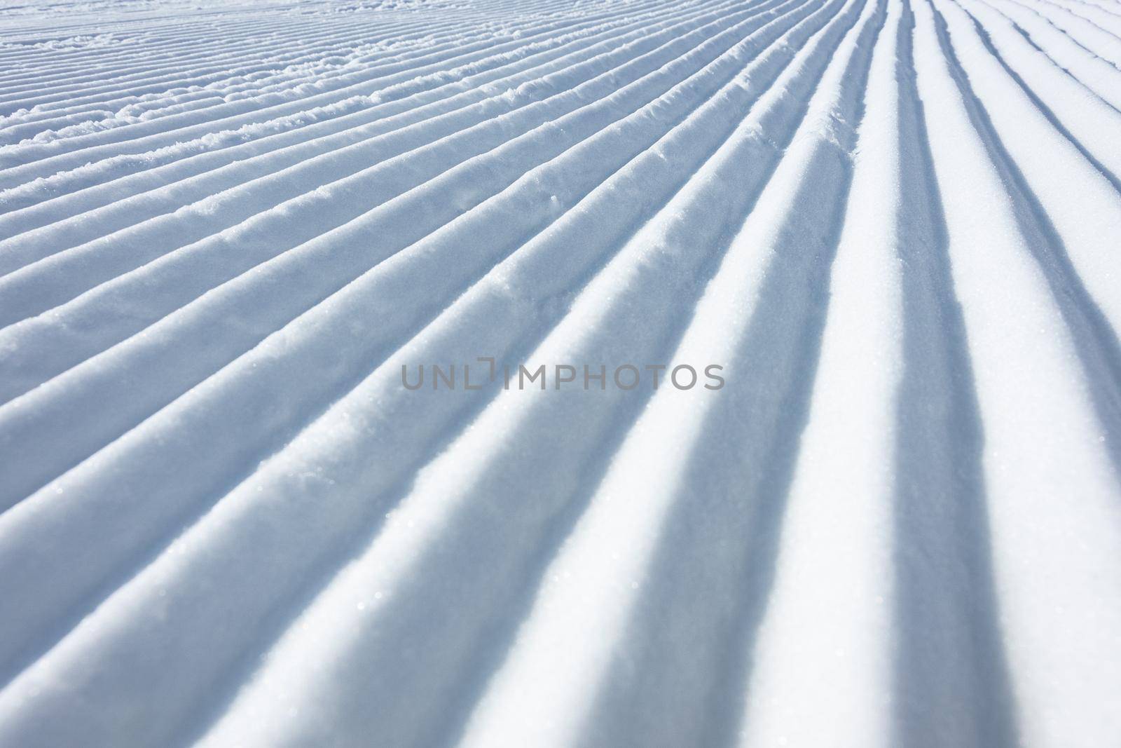 Geometry track lines on a ski slope left by a snowcat as a texture background.