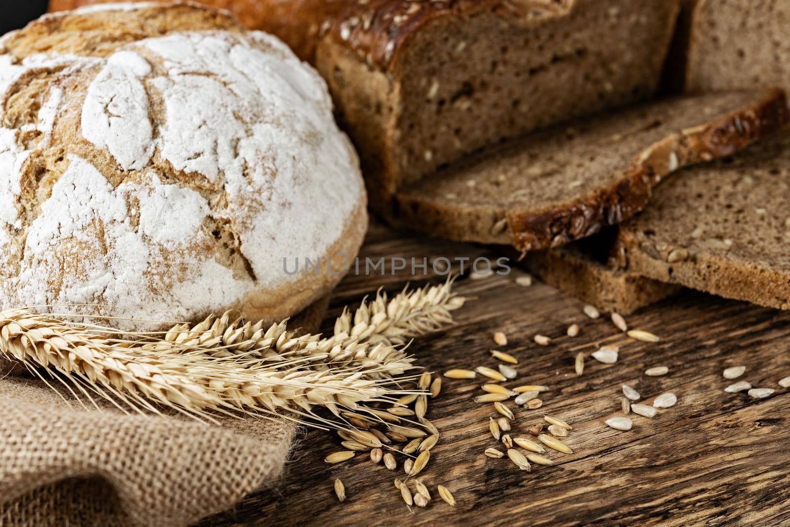 Group of dark breads with wheat, sunflower and rye grains on a wooden vintage table.
