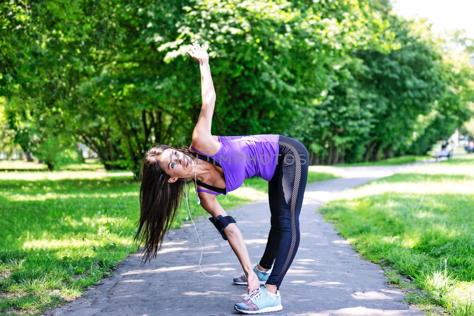 Beautiful young girl stretching before jogging in the park on a sunny morning.