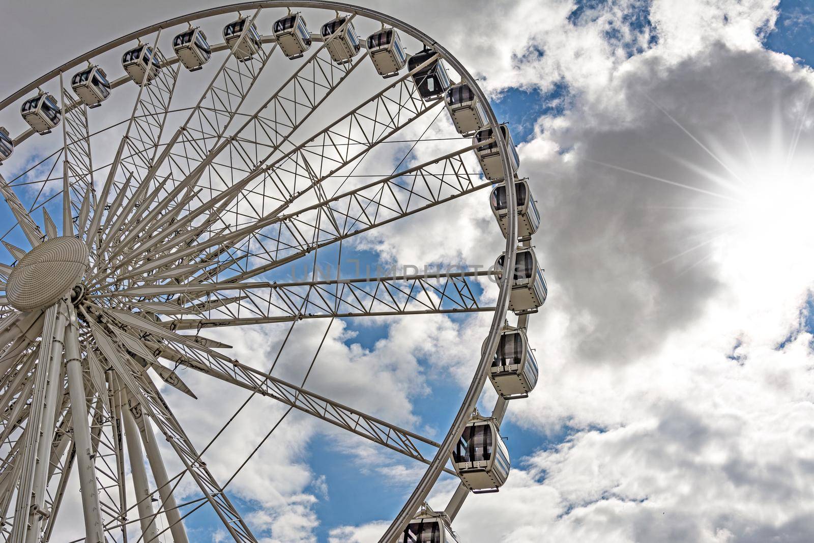 Part of a big ferris wheel on a cloudy sky background.