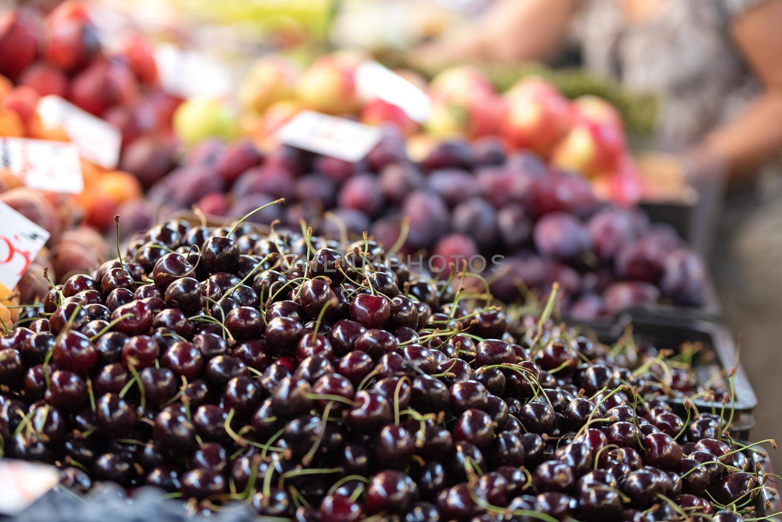 Fresh cherries and other fruits for sale in a traditional farmer market in close-up ( selective focus).