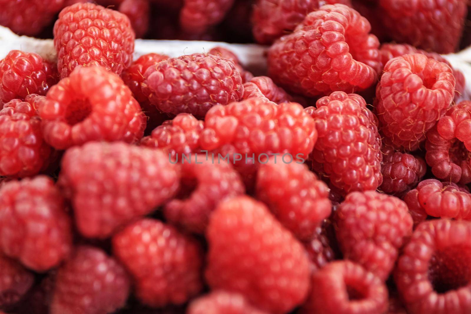 Background of fresh and juicy raspberries for sale at the market in close-up.