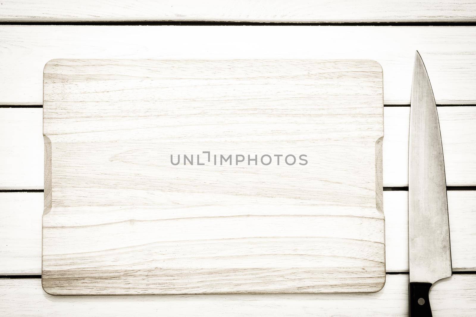 Rustic culinary template - top view of an empty cutting board and knife on a white wooden table.