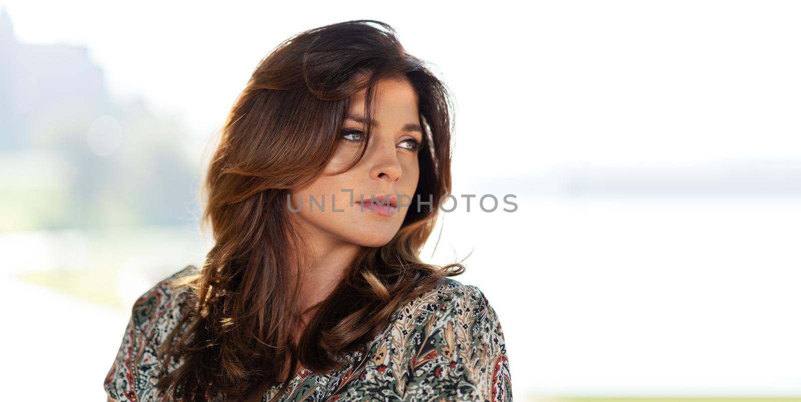 Portrait of a lovely fashion model with nice hairstyle posing outdoors in the seacoast resort on a sunny day (copy space)