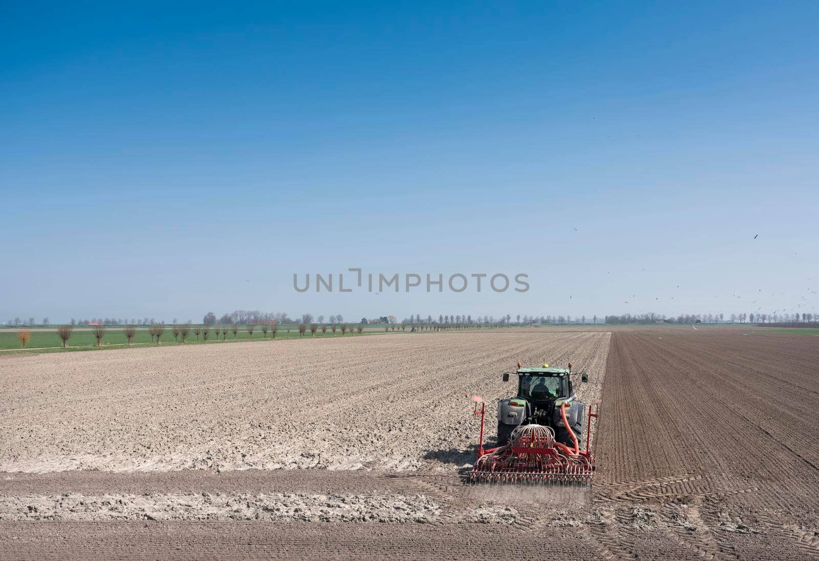 wissenkerke, netherlands, 31 march 2021: farmer works his land on rural countryside of noord beveland in dutch province zeeland on sunny spring day under blue sky in the netherlands