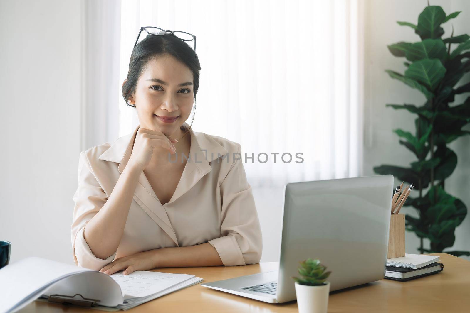 Portrait of businesswoman with laptop while checklist on a document at her office