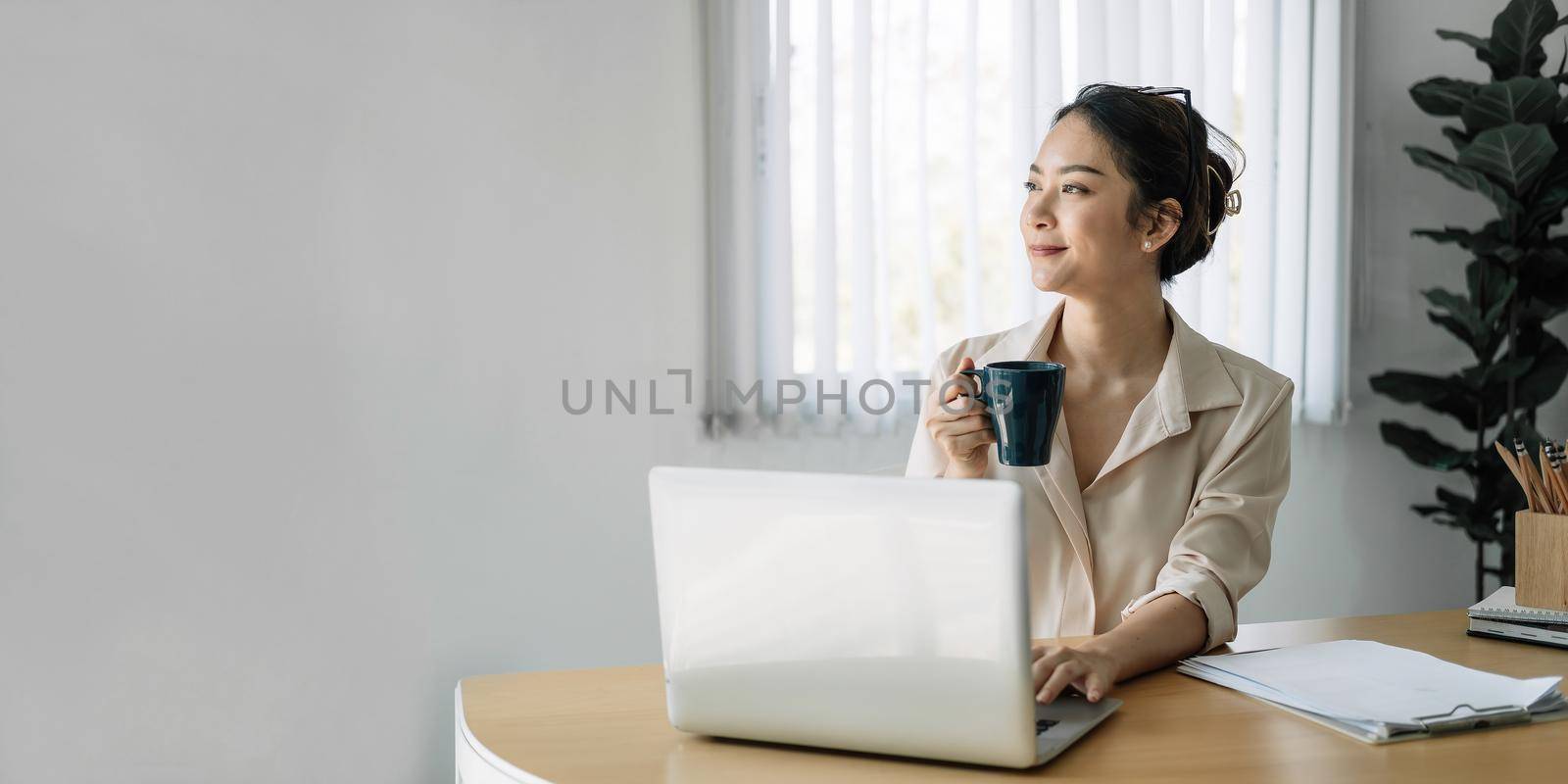 Young asian businesswoman beautiful charming smiling holds cup in the office.