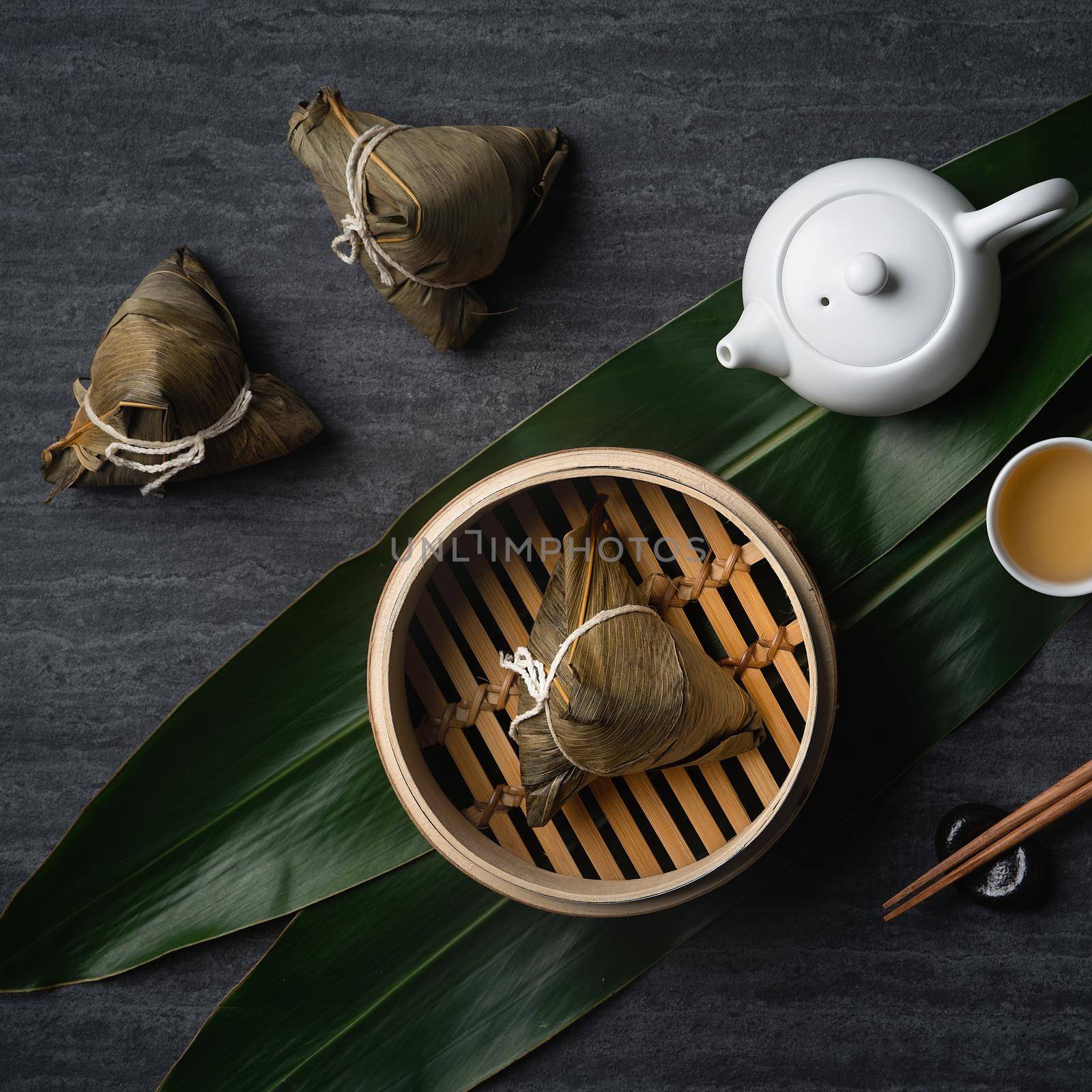 Zongzi rice dumpling top view for Chinese traditional Dragon Boat Festival (Duanwu Festival) over dark black slate background.