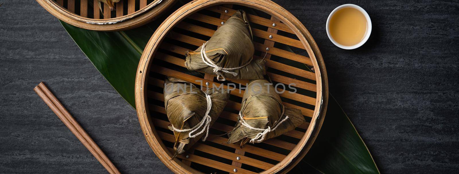Zongzi rice dumpling top view for Chinese traditional Dragon Boat Festival (Duanwu Festival) over dark black slate background.