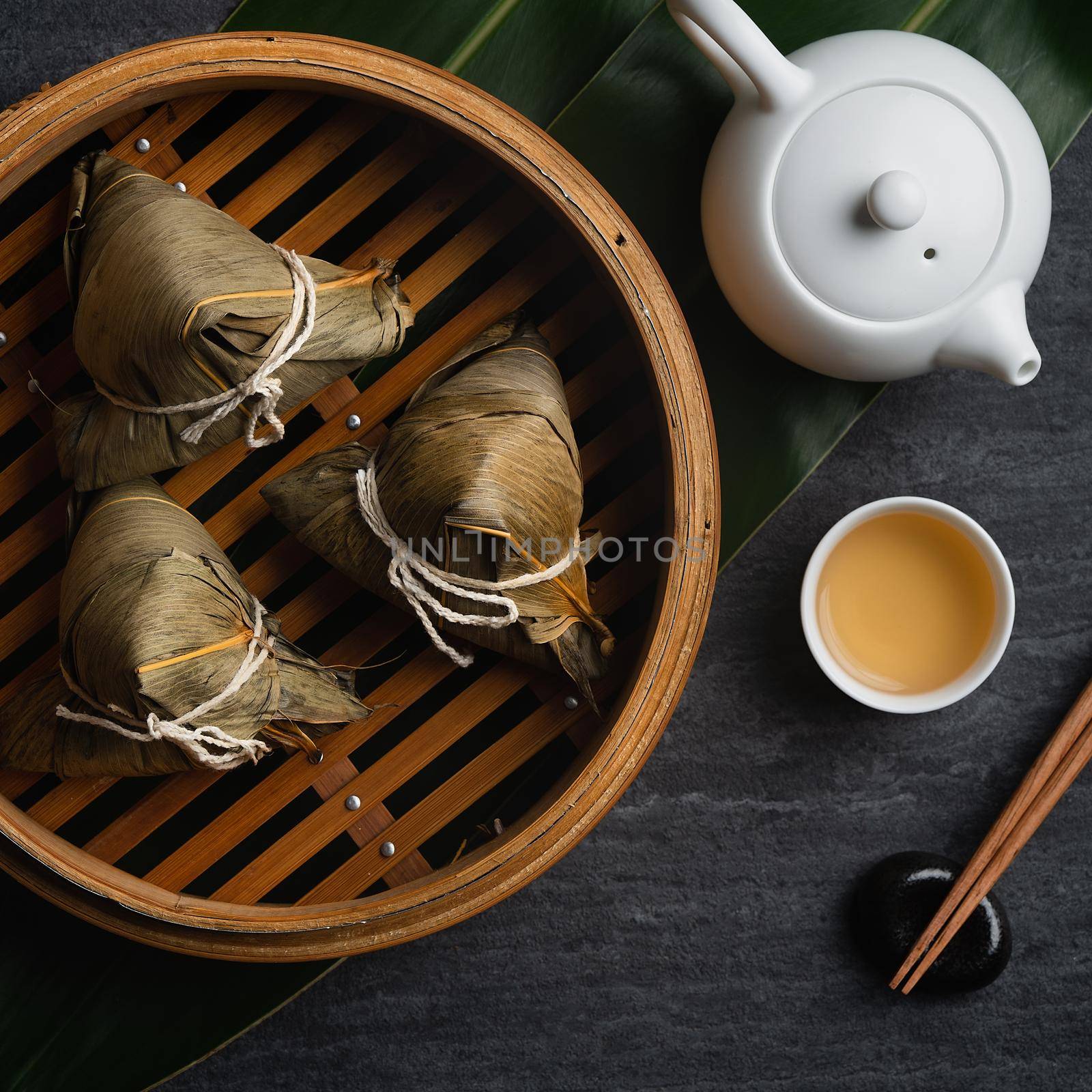 Zongzi rice dumpling top view for Chinese traditional Dragon Boat Festival (Duanwu Festival) over dark black slate background.