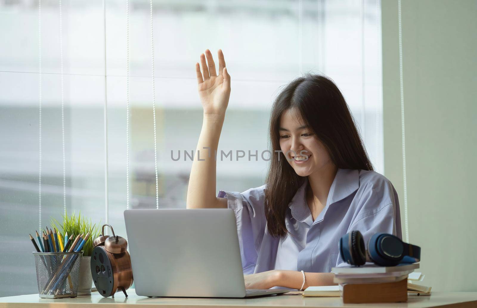 Online education. The girl raises her hand to answer the teacher's question at home.