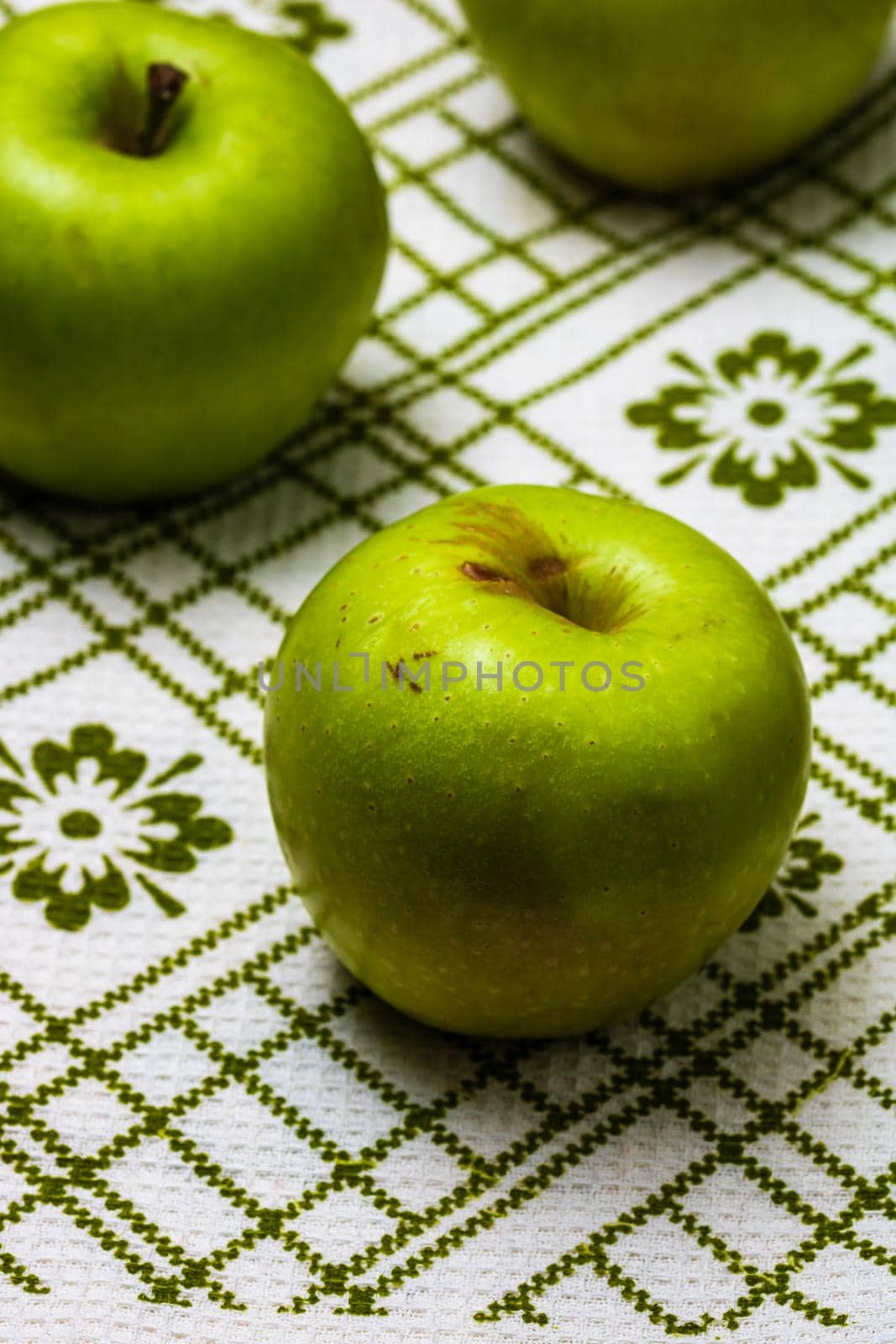 Ripe green apples on a rustic napkin on wooden table.