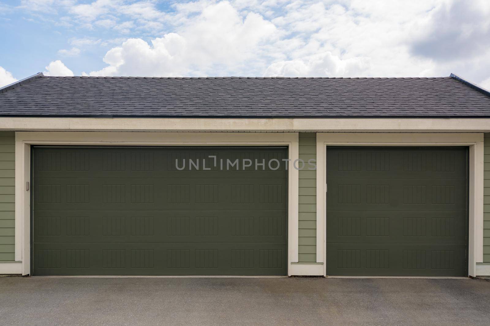 Three car garage with wide double door on cloudy sky background