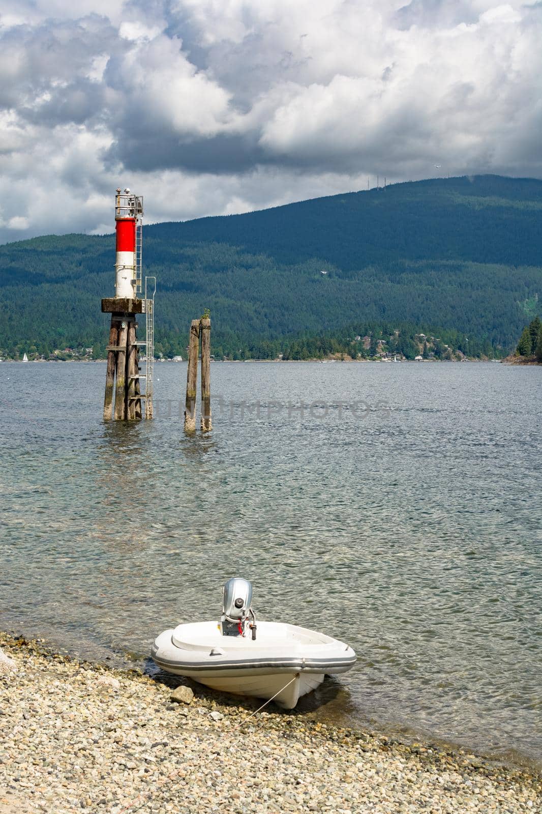 Motorized boat moored at stone shore with ship channel light behind