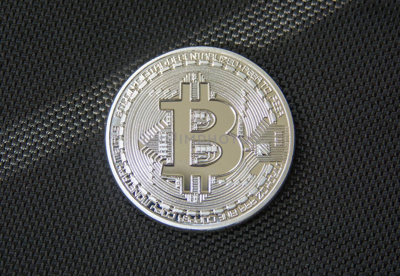 Obverse of metal bitcoin on black fiber background. Crypto currency coin