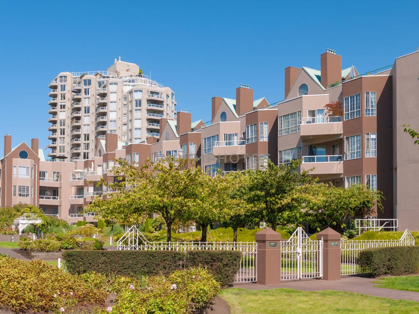 Gated residential complex with recreational area in front. Cityscape on blue sky background
