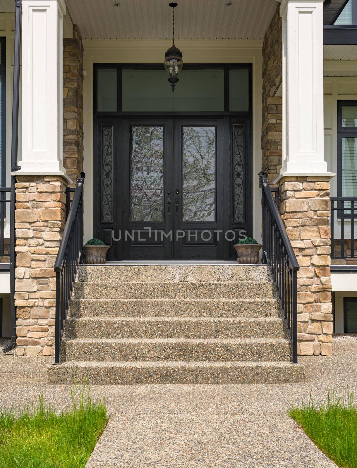 Main entrance of residential house with door steps and nice flower pots at the door on bright sunny day