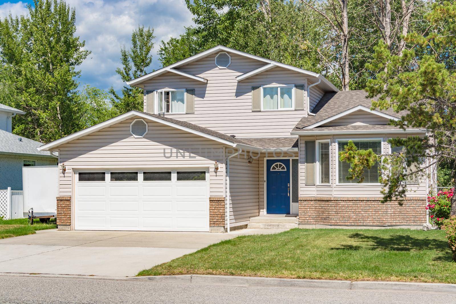 A perfect neighbourhood. Family house with landscaped front yard on sunny day in British Columbia