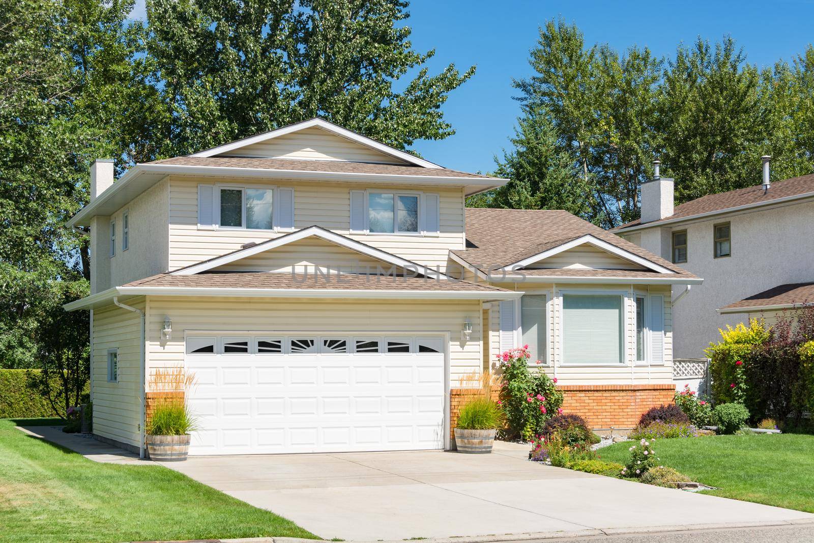 A perfect neighbourhood. Family house with landscaped front yard on sunny day in British Columbia