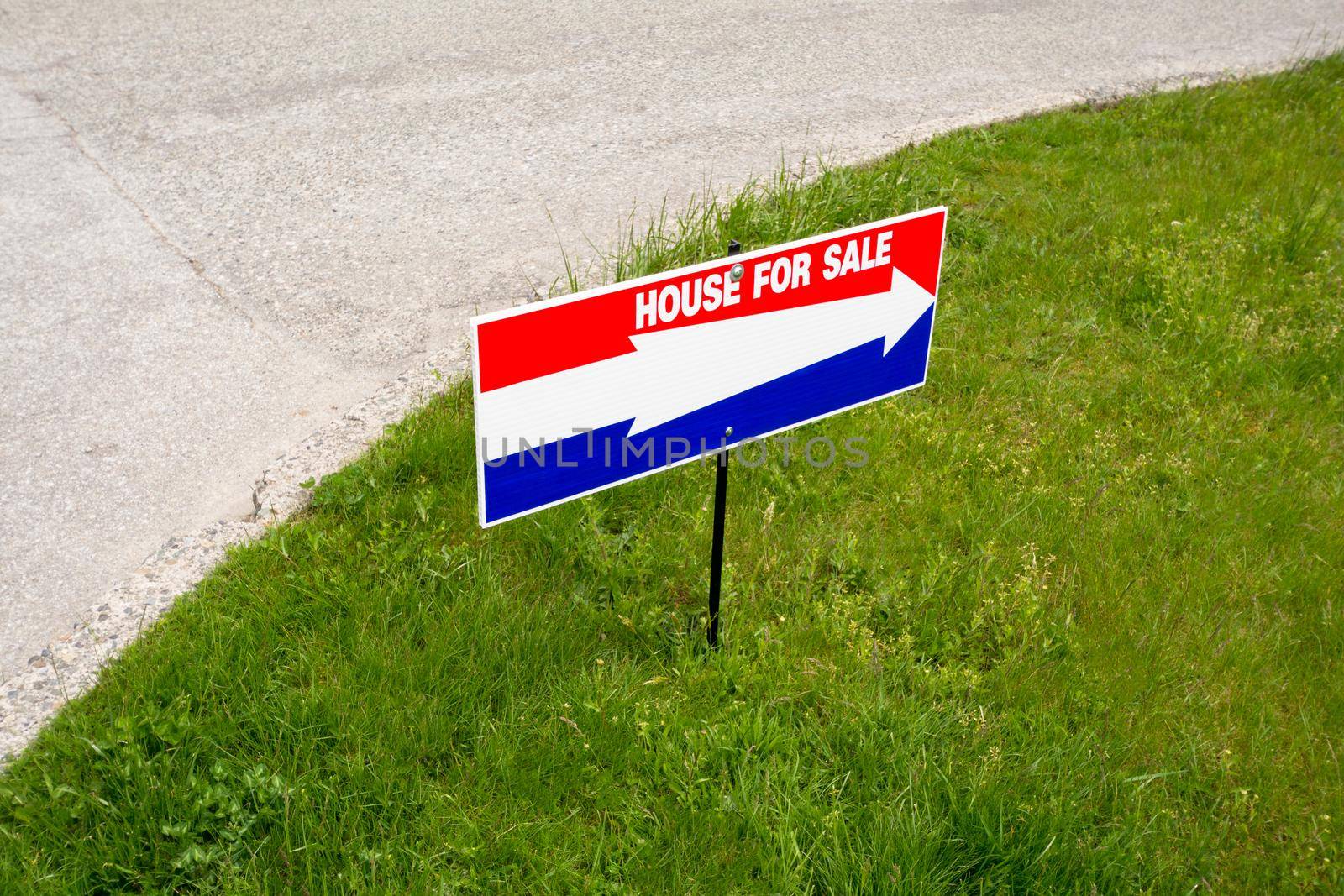 'House for sale' open house directional pointer on green lawn at road turn