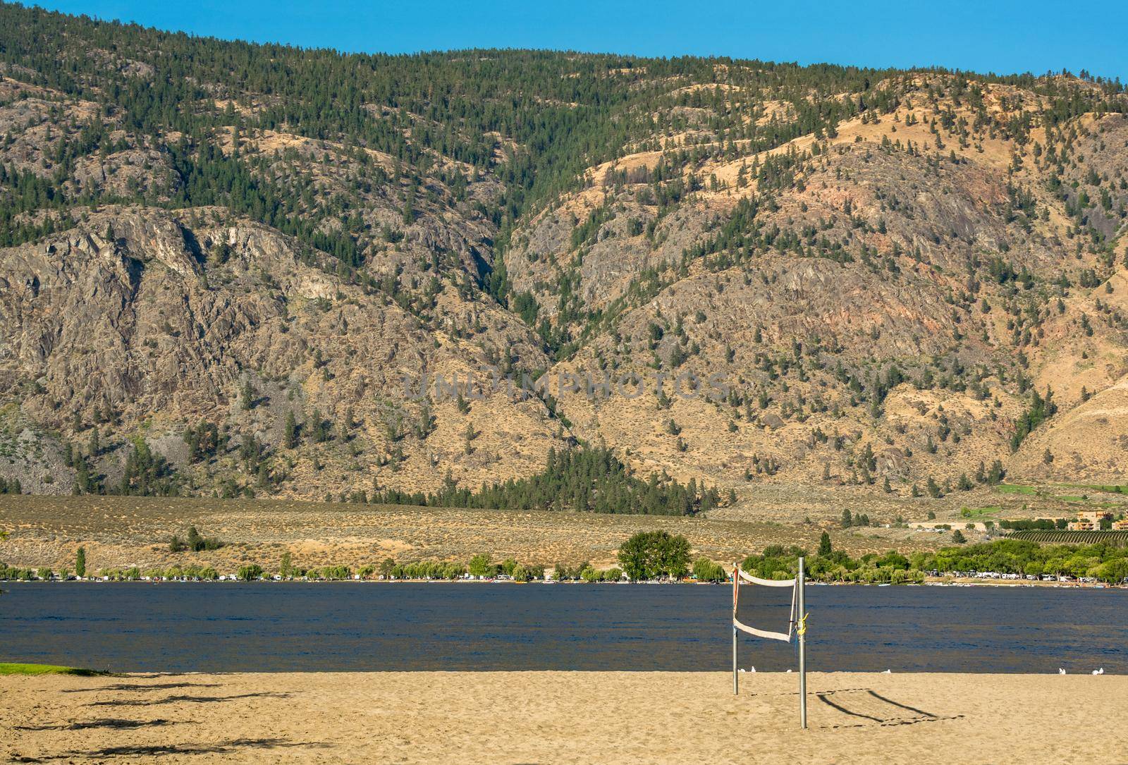 Sand beach with installed valleyball net for the game. Osoyoos lake view with mountain background