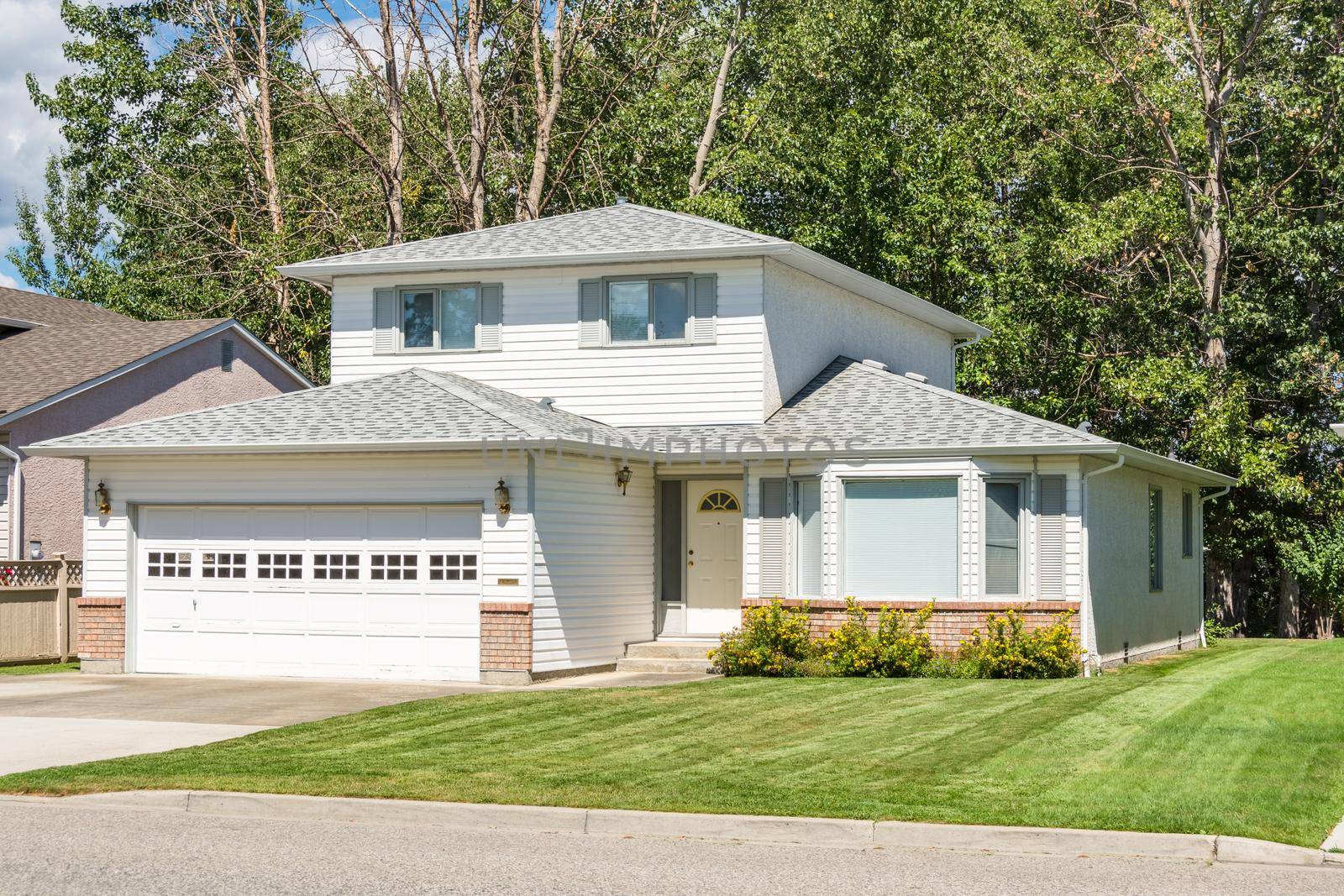 A perfect neighbourhood. Family house with landscaped front yard on sunny day in British Columbia