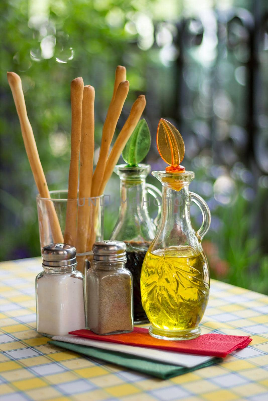 Italian serving. Table set of olive oil, bread sticks, salt, pepper. Vertical by VeraVerano