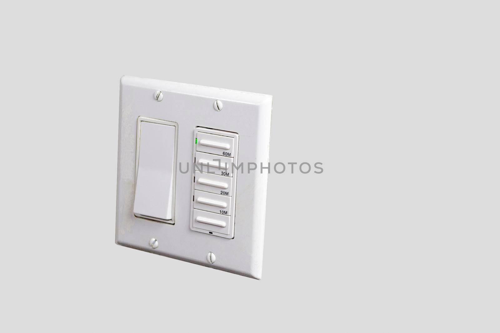 White light switch and fan relay mounted on a white wall in a toilet of a wooden house