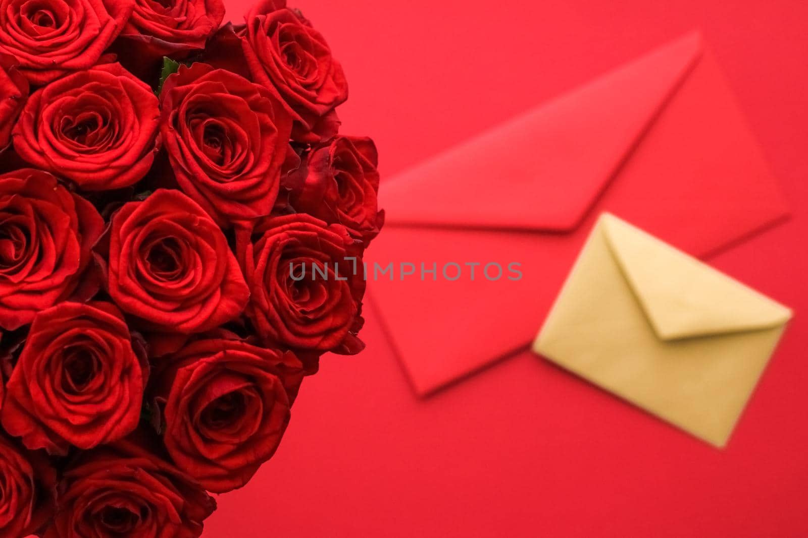 Holiday gift, flowers flatlay and happy relationship concept - Love letter and flower delivery service on Valentines Day, luxury bouquet of red roses and card envelopes on red background