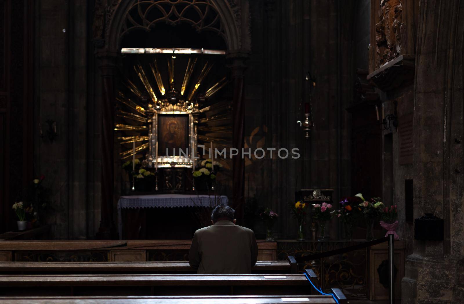 Wien - April 3, 2021: man praying on a pew in a church.