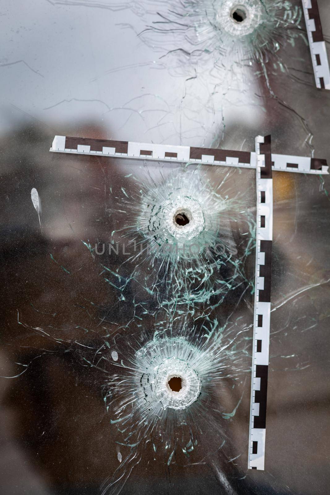 bullet holes in a glass shop window marked with a police tape.