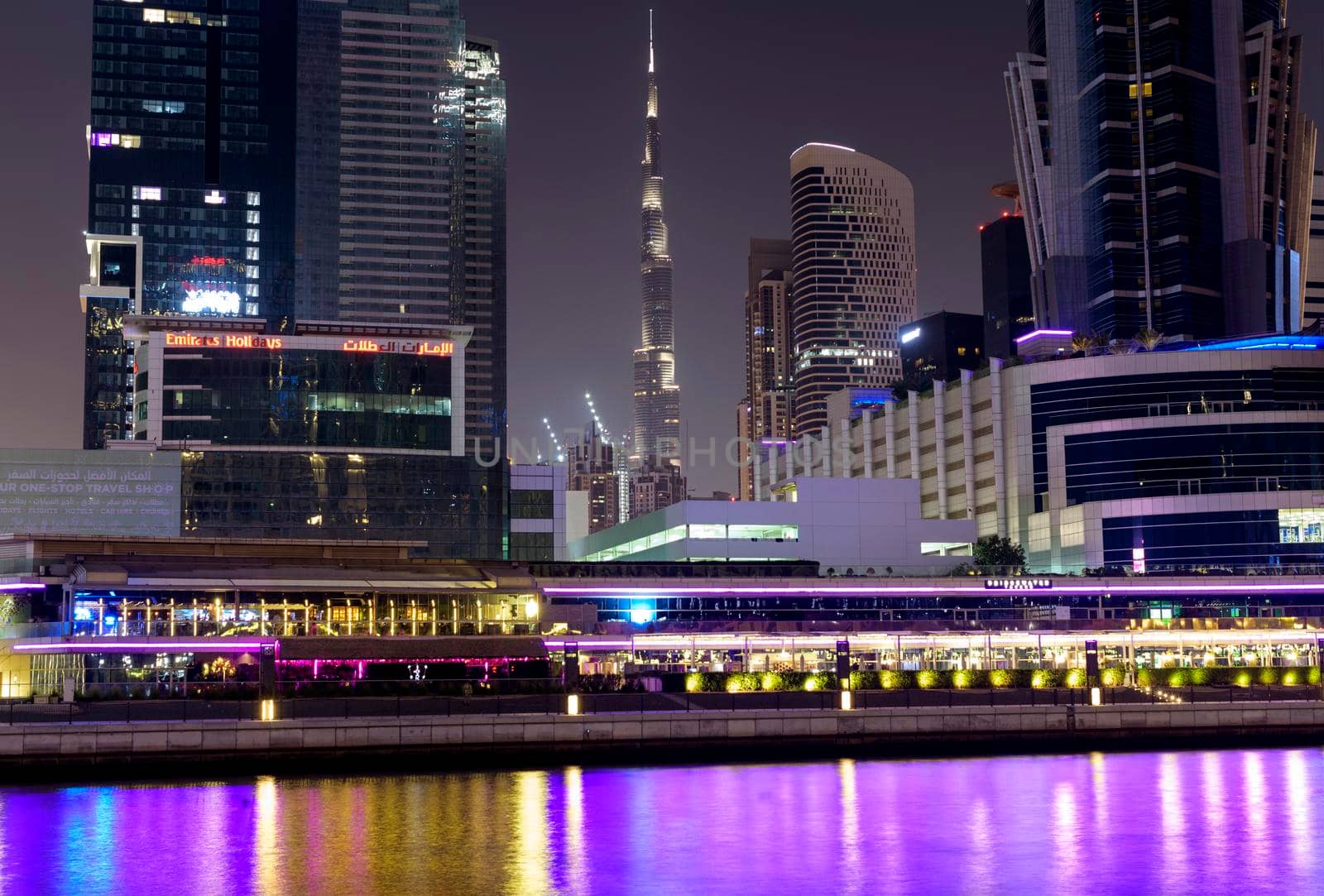 DUBAI, UAE 6th nov 2020 -view of the Burj khalifa surrounded with buildings and hotels facing the Colorful illuminated dubai canal boardwalk Waterfall in Dubai,United Arab Emirates, Middle East