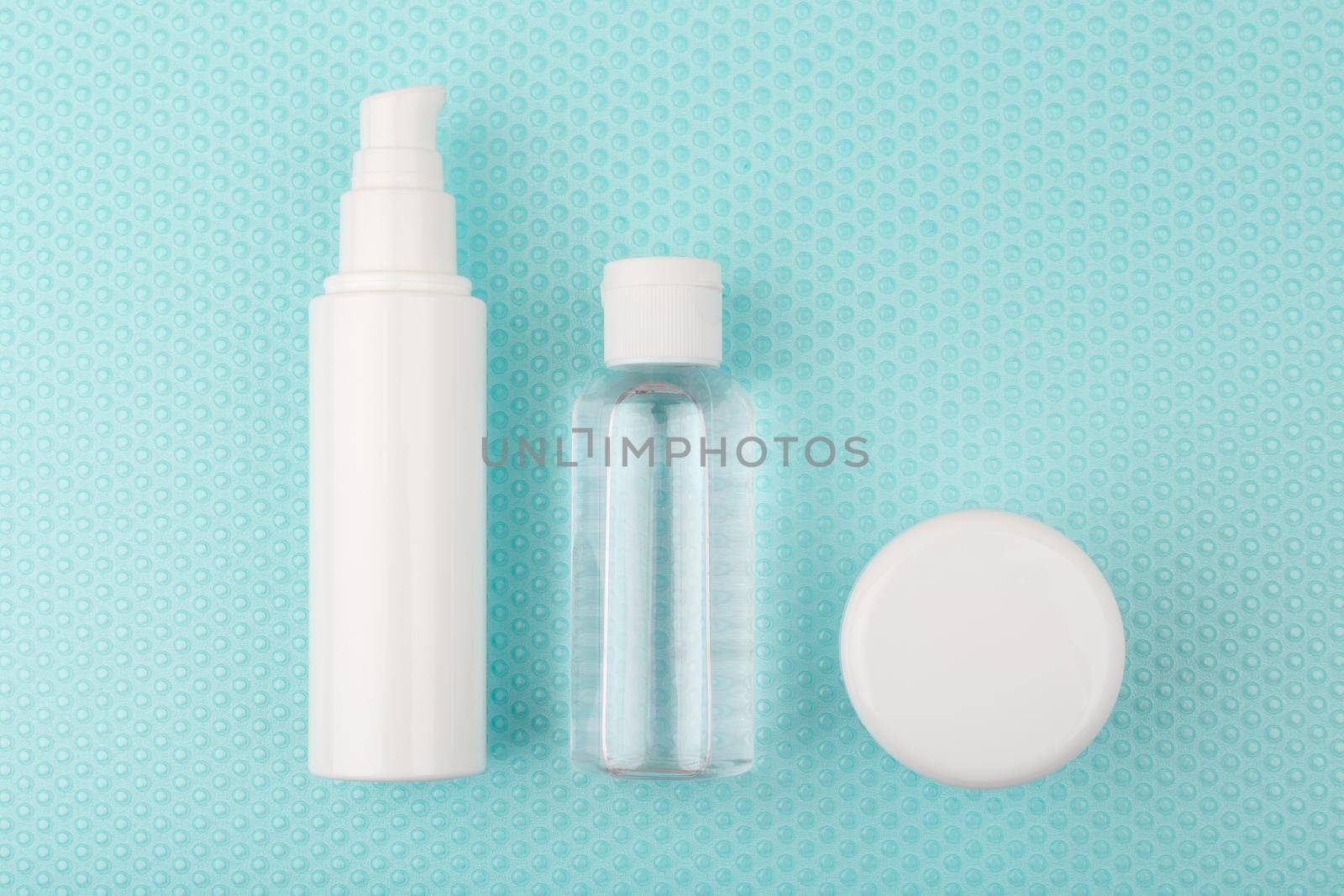 Toiletries on light blue background with bubbles. Moisturizing cream, exfoliating lotion and under eye cream set for daily skin care routine