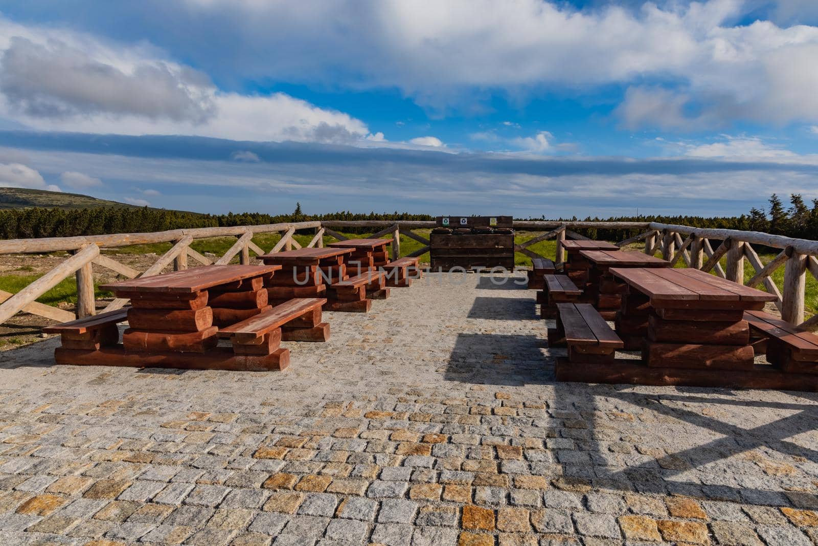 Small square with wooden tables and benches next to mountain trail at Giant Mountains by Wierzchu