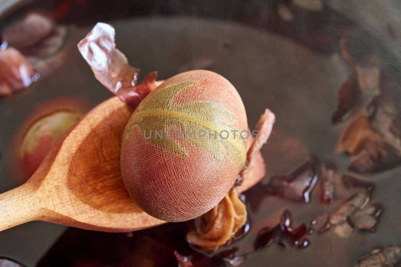 Taking Easter eggs dyed with onion peels out of boiling water with a wooden spoon by madeleine_steinbach