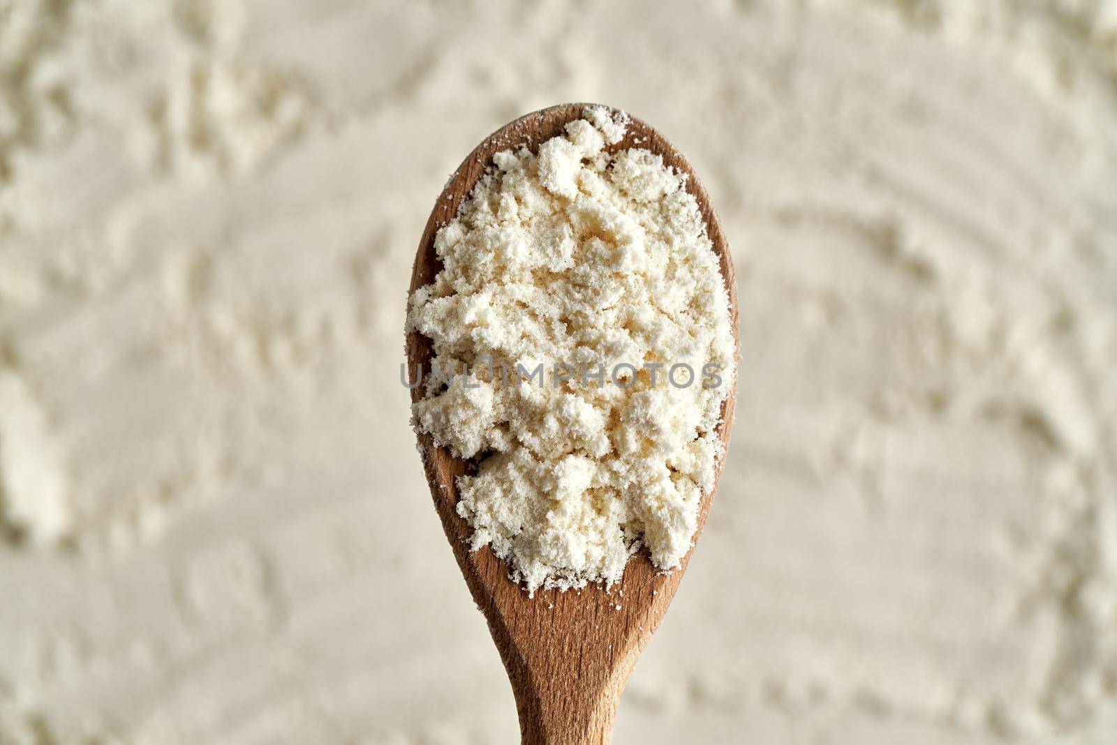 Whey protein powder on a wooden spoon, top view