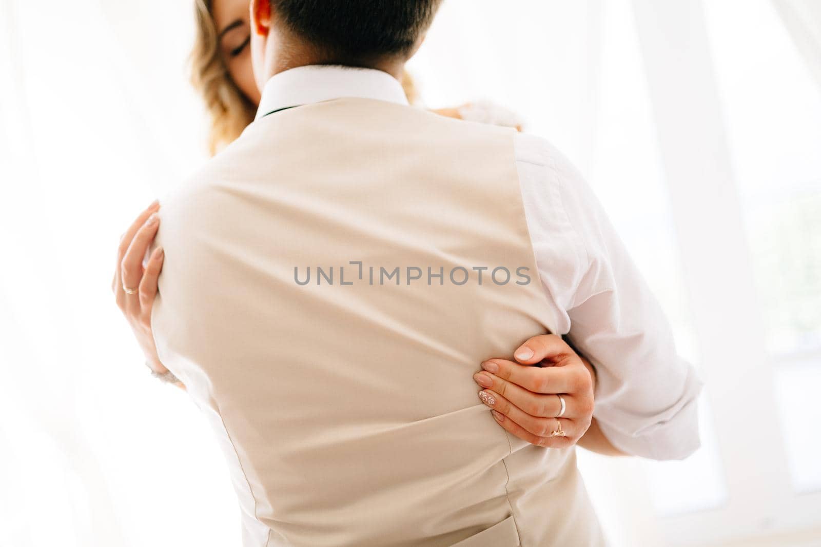 The bride hugs the groom tightly, the groom kisses her, the view from the back of the groom . High quality photo