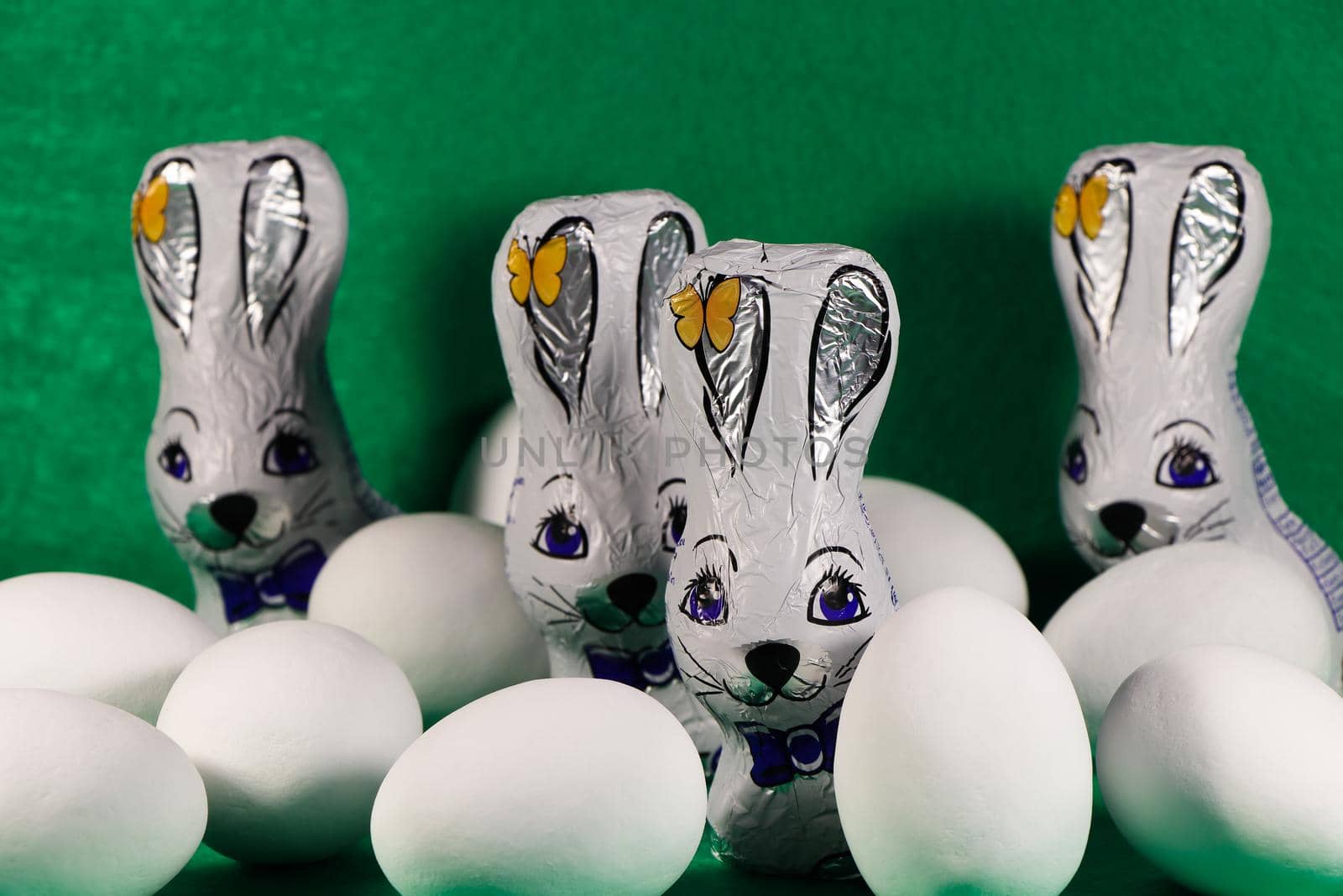 Foil wrapped chocolate Easter bunnies with candy coated eggs on green