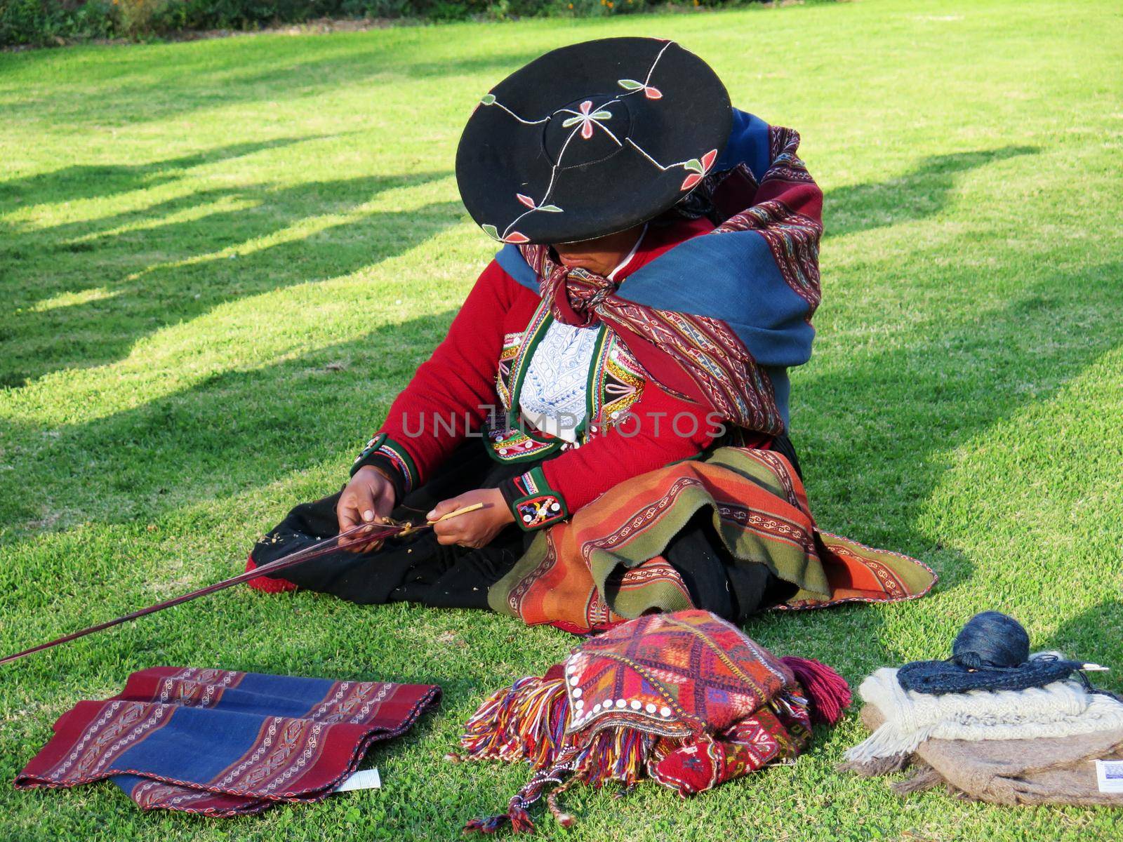 Close up of Peruvian lady in authentic dress spinning yarn by hand by aroas