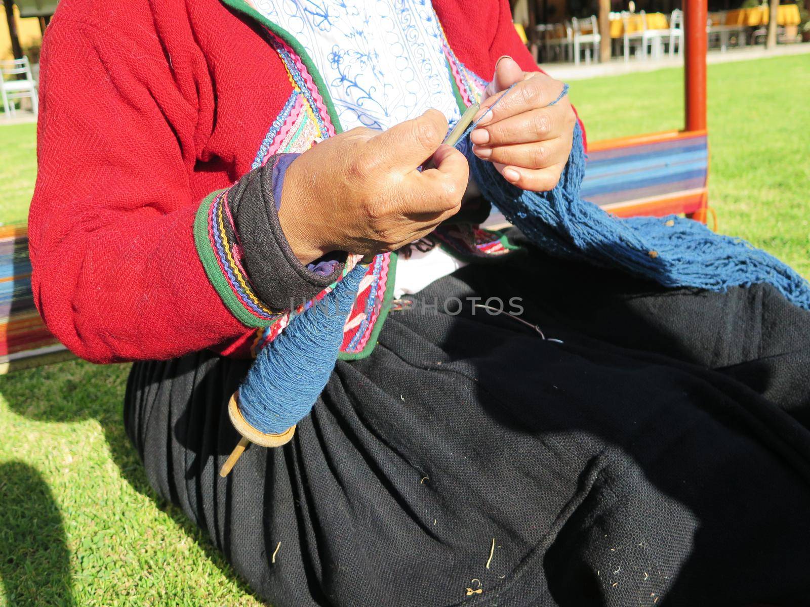 Close up of Peruvian lady in authentic dress spinning yarn by hand by aroas