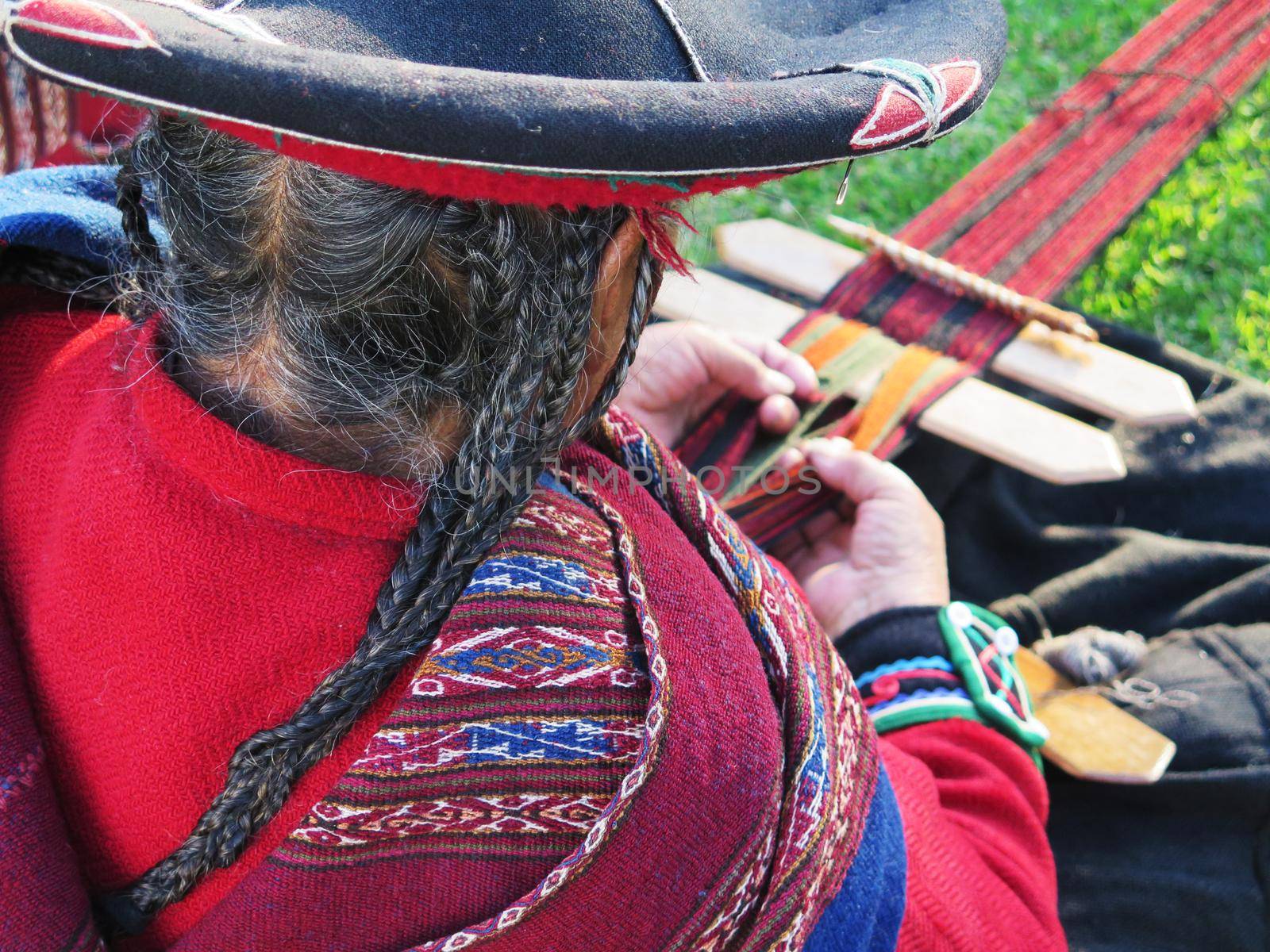 Close up of Peruvian lady in authentic dress spinning yarn by hand by aroas