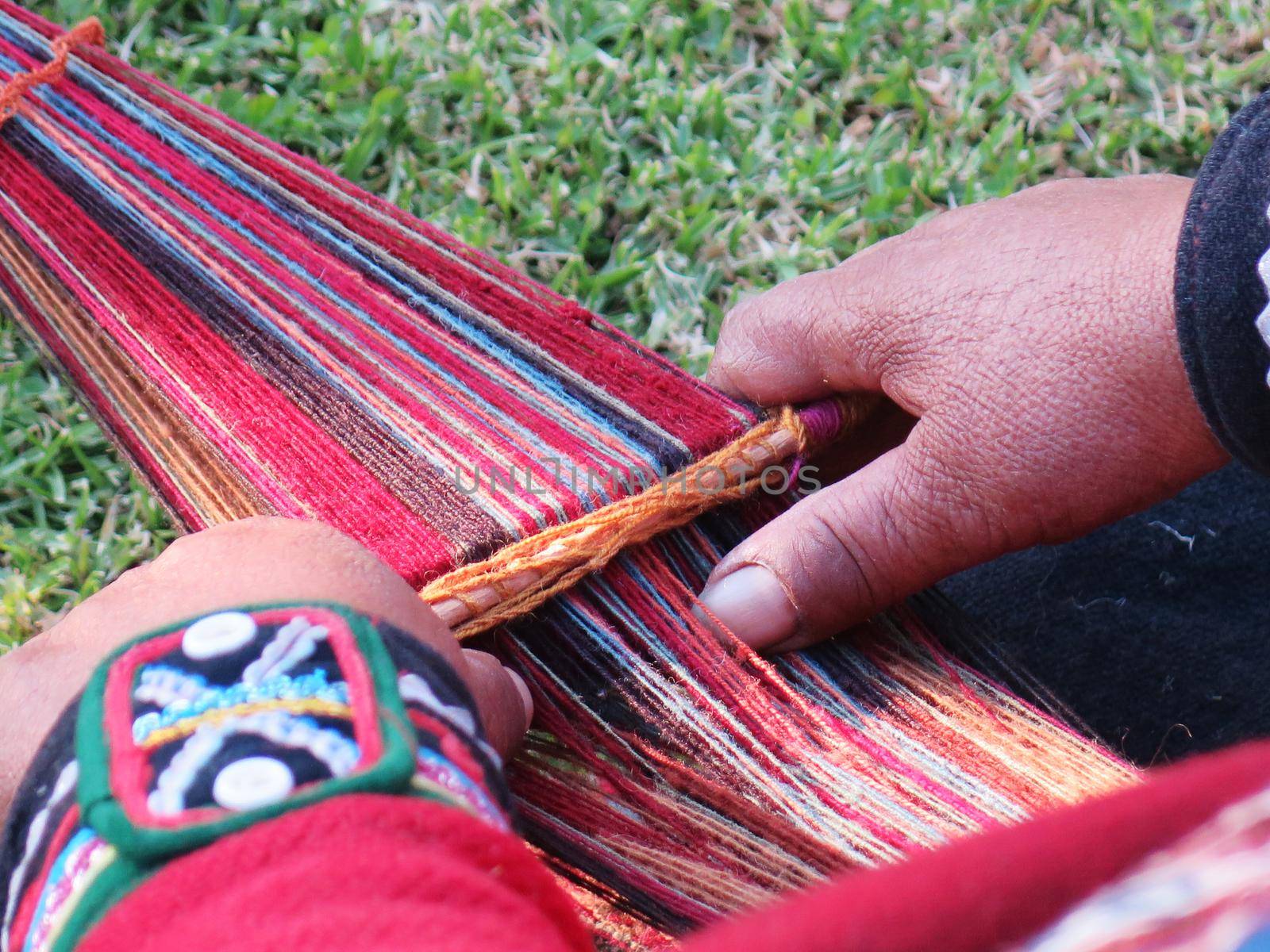 Close up of Peruvian lady in authentic dress spinning yarn by hand by aroas