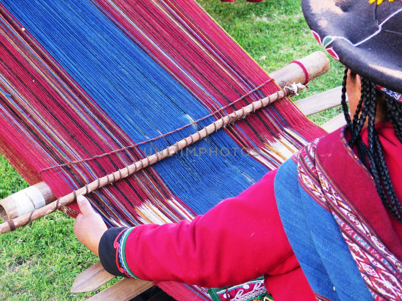 Close up of Peruvian lady in authentic dress spinning yarn by hand by aroas